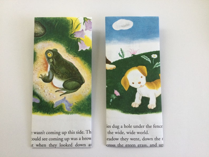 May include: Two rectangular bookmarks with illustrations. One shows a green frog with a yellow eye, the other a puppy in a field. Text is visible at the bottom of each bookmark.