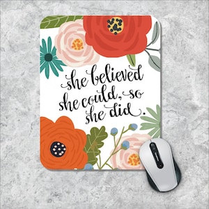 May include: A white mouse pad with a floral design and the text "she believed she could, so she did."