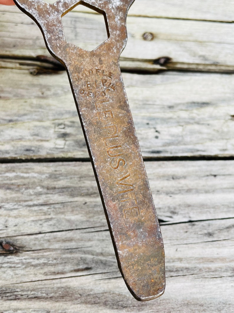 May include: A rusty metal wrench with a hexagonal opening and the words 'LUSVITE' and 'RIFLE' stamped on the handle.