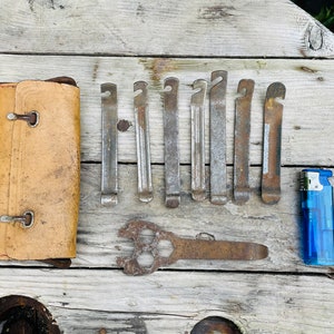 May include: A set of tire levers, a wrench, and a blue lighter on a wooden surface. The tire levers are made of metal and have a rusty finish. The wrench is also made of metal and has a rusty finish. The lighter is made of plastic and has a blue finish.