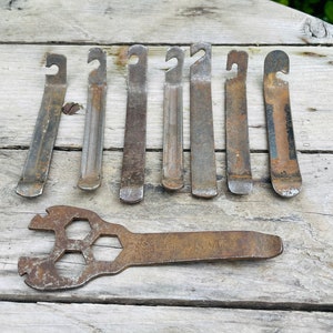 May include: Eight rusty metal tire levers and a rusty metal wrench with a hexagonal hole in the center. The wrench has the words 'THIS WAS MY' stamped on it.