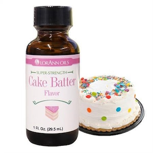 May include: A brown glass bottle with a white label that reads "LORANN OILS SUPER-STRENGTH Cake Batter Flavor 1 Fl. Oz. (29.5 mL)". The bottle is next to a white frosted cake with colorful sprinkles and dots.