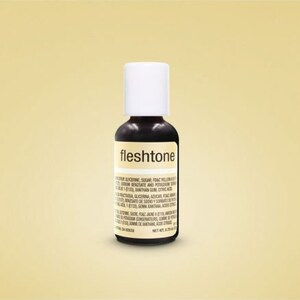 May include: A small, clear glass bottle with a black label that reads "fleshtone". The bottle contains a dark brown liquid and is labeled with a list of ingredients.