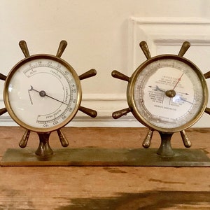 May include: A brass nautical-themed weather station with two round gauges. The left gauge is a thermometer with a black needle and markings in Fahrenheit. The right gauge is a barometer with a red needle and markings for "In Inches" and "Anch Barometer".