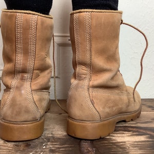 Puede incluir: Un par de botas de cuero marr&oacute;n con cordones. Las botas tienen un dise&ntilde;o cosido en la parte posterior y una suela gruesa.