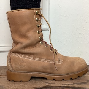 Puede incluir: Un par de botas de cuero marr&oacute;n con cordones y suela gruesa.
