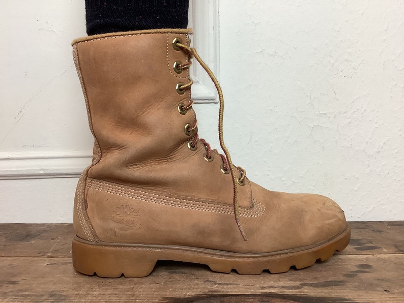 Puede incluir: Un par de botas de cuero marr&oacute;n con cordones y suela gruesa.