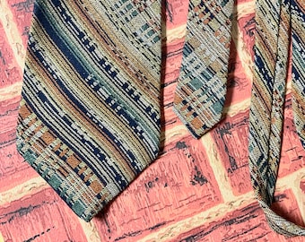 Puede incluir: Dos corbatas estampadas con un diseño geométrico en tonos marrones, naranjas, verdes y azules. Las corbatas están dispuestas sobre una superficie estampada rosa y blanca.