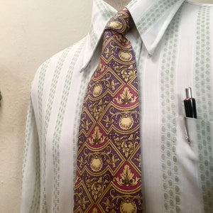 Puede incluir: Una camisa blanca con rayas verticales verdes y una corbata estampada. La corbata tiene un diseño morado, dorado y rojo. Un bolígrafo plateado está en el bolsillo de la camisa.
