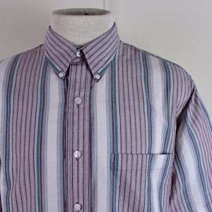 May include: A short-sleeved button-down shirt with a striped pattern in shades of purple, blue, and white.