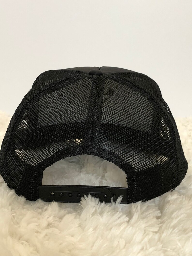 May include: Black mesh trucker hat with a black adjustable strap in the back.