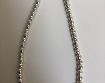 May include: A silver necklace with round beads.