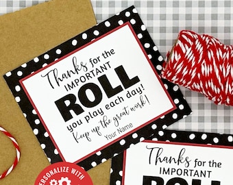 May include: Two square gift tags with a black polka dot border and red trim, featuring the text "Thanks for the IMPORTANT ROLL." A roll of red and white twine and a brown tag are also present. A red sticker says "Personalize with Corjl!"