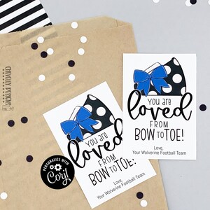 May include: Two printable gift tags with a black and white polka dot bow with a blue ribbon. The text on the tags reads "You are loved from bow to toe!" and "Love, Your Wolverine Football Team".