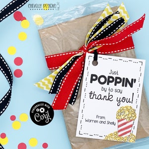 May include: A white gift tag with black text that reads "Just Poppin' by to say thank you!" with a cartoon image of a red and white striped popcorn bucket with yellow popcorn. The tag is tied to a brown paper bag with red, black, and yellow ribbon.