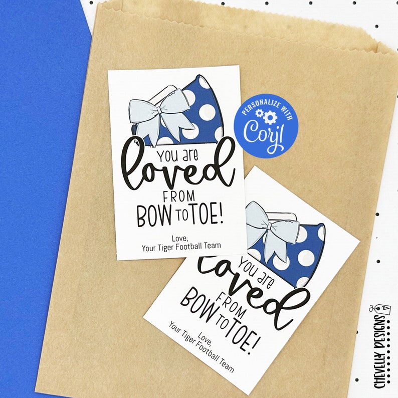 Puede incluir: Dos etiquetas de regalo blancas con meg&aacute;fonos de lunares azules y blancos y un lazo blanco. El texto en las etiquetas dice "You are loved from bow to toe!" y "You are loved from bow to toe!" con la palabra "loved" escrita en una fuente grande y estilizada. Las etiquetas est&aacute;n en una bolsa de papel marr&oacute;n con lunares blancos.