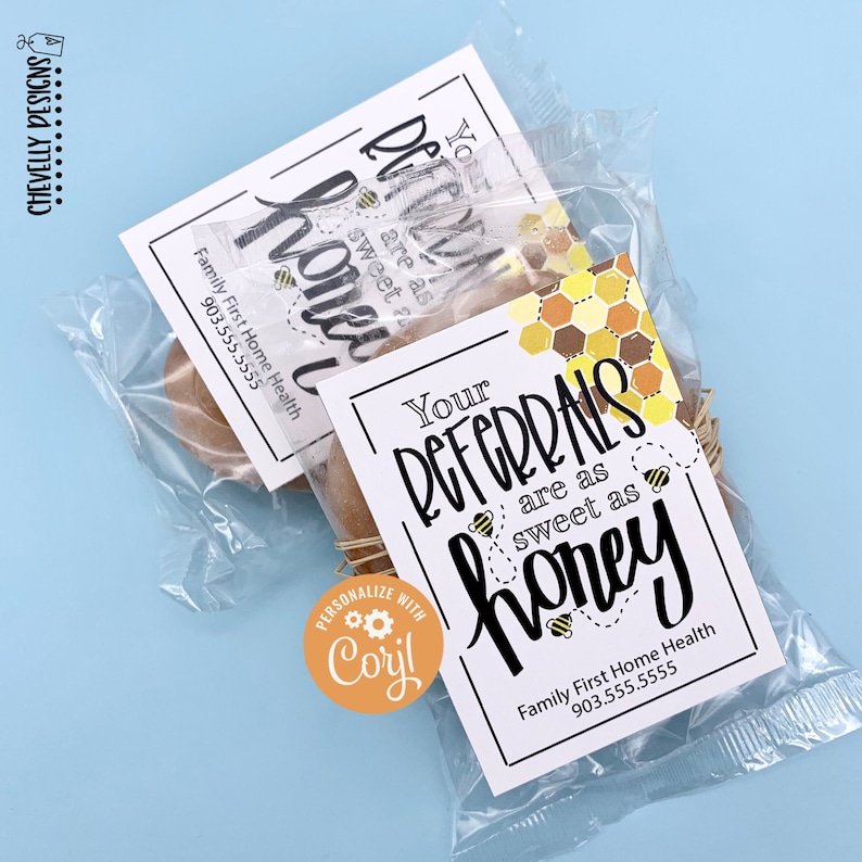 May include: Two small bags of honey sticks with a white tag that says "Your referrals are as sweet as honey" and a bee graphic. The tag also includes the business name "Family First Home Health" and a phone number. A round orange sticker with the text "Personalize with Coril" is on the bag.