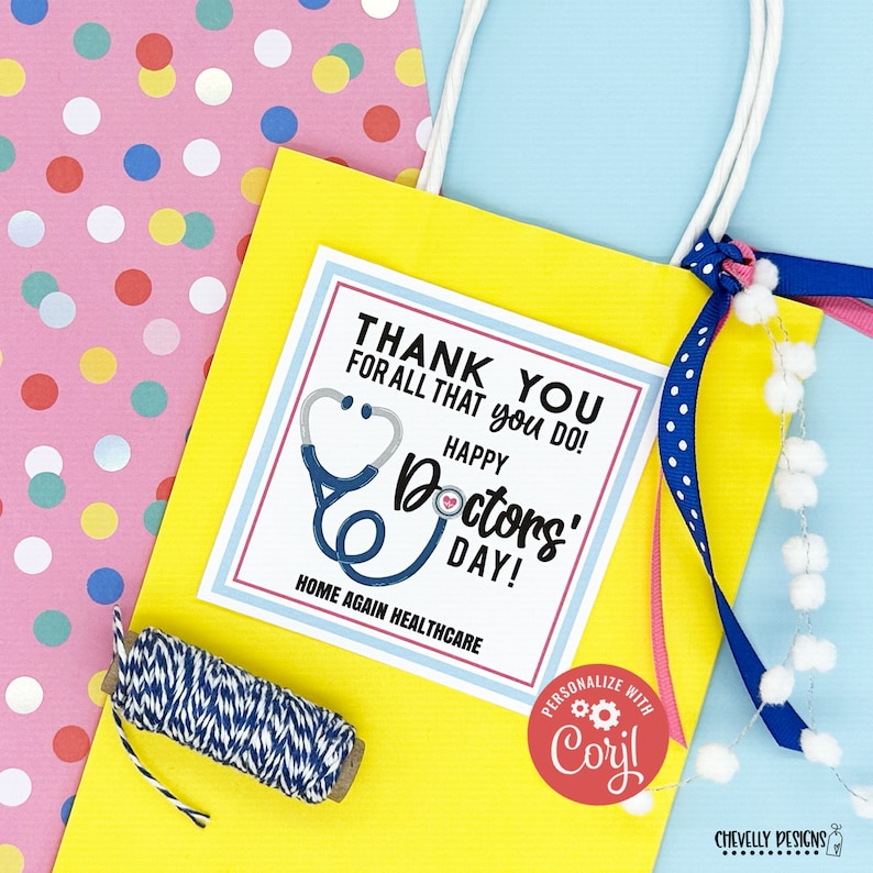 May include: A yellow gift bag with a blue and white polka dot ribbon. The bag contains a card that says "Thank You for all that you do! Happy Doctors' Day! Home Again Healthcare". The card has a blue stethoscope with a red heart on it. The bag also has a red circle with the text "Personalize with Coril" on it.