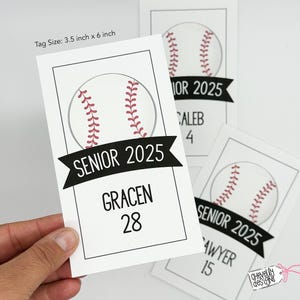 May include: White baseball-themed gift tags with black text. The tags feature a baseball graphic with red stitching and the text "Senior 2025". Each tag has a name and number, such as "Gracen 28".
