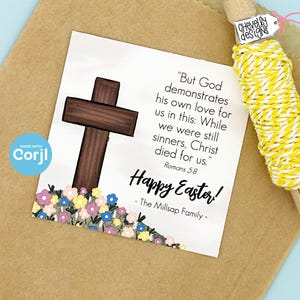 Puede incluir: Una tarjeta blanca con una cruz de madera marr&oacute;n, flores rosas, azules y amarillas, y el texto "Pero Dios demuestra su amor por nosotros en esto: Mientras a&uacute;n &eacute;ramos pecadores, Cristo muri&oacute; por nosotros." Romanos 5:8 &iexcl;Feliz Pascua! - La familia Millsap -