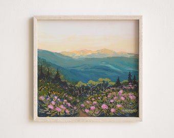 Puede incluir: Un cuadro cuadrado enmarcado que representa un paisaje de montaña al atardecer. El primer plano muestra flores de rododendro rosas y árboles de color verde oscuro. El fondo muestra montañas azules bajo un cielo amarillo pálido.