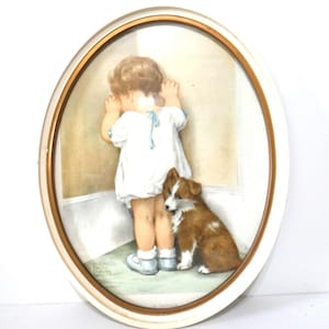 May include: An oval framed print titled In Disgrace featuring a child with curly hair wearing a white dress with blue ribbons standing in a corner facing the wall with a small brown and white puppy sitting beside them on a green floor.