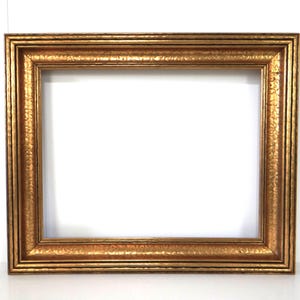 May include: A rectangular, gold-colored picture frame with a textured surface. The frame has a wide, ornate border with multiple layers and a bright, reflective finish. The interior is empty, revealing a white background.