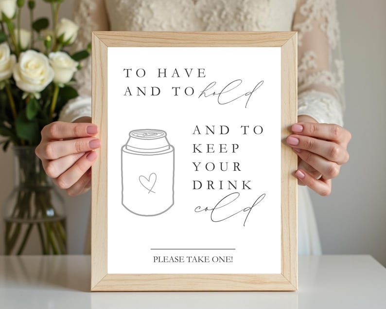 May include: A light wood frame containing a white sign with black text that reads: TO HAVE AND TO hold AND TO KEEP YOUR DRINK cold. Below the text is a line drawing of a beverage can cooler with a small heart outline and the text PLEASE TAKE ONE!