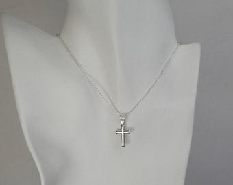 May include: A silver chain necklace with a small silver cross pendant.