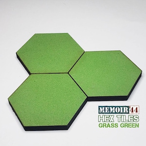 May include: Three green hexagonal game tiles with black borders. The tiles are made of foam and have a textured surface. The text "MEMOIR '44 HEX TILES GRASS GREEN" is printed below the tiles.