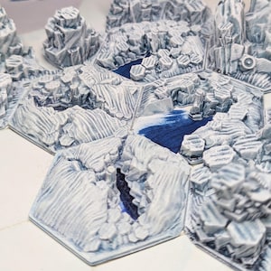 May include: A collection of hexagonal terrain tiles depicting an icy landscape. The tiles feature detailed, textured rock formations, with blue water features and snow-covered peaks. Ideal for tabletop gaming or model scenery.