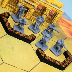 Może przedstawiać: Zestaw plastikowych żołnierzyków w miniaturze w pustynnym otoczeniu. Żołnierze trzymają karabiny i są ustawieni za drewnianą barykadą. Barykada jest wykonana z brązowego drewna i ma czarną podstawę.