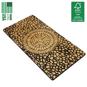 Könnte beinhalten: Rechteckiger Holz-Lesezeichen mit einem detaillierten Gravurmuster. Das Lesezeichen zeigt ein Kopfsteinpflastermuster mit einem kreisförmigen Kanaldeckel-Design in der Mitte. Der Text "MADE IN THE USA" ist auf der linken Seite aufgedruckt.