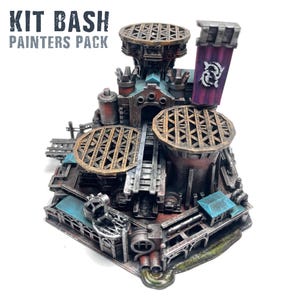 May include: A detailed miniature model with the text "KIT BASH PAINTERS PACK". The model features a complex structure with multiple levels, including circular platforms with intricate metalwork, a purple banner, and various pipes and architectural details. The color palette includes shades of brown, teal, and purple.