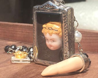 Creepy cute vintage porcelain doll necklace with silver plated locket and doll parts. Unique statement jewellery and wearable art pendent.