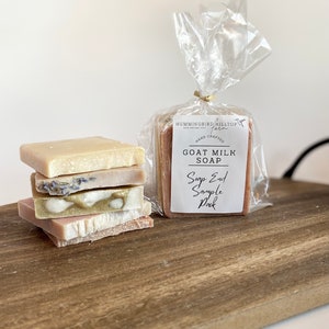 May include: A stack of five goat milk soap bars in various colors and scents, including lavender, green, and pink. The soap bars are packaged in a clear plastic bag with a label that reads "Hummingbird Hilltop Farm Hand Crafted Goat Milk Soap Soap End Sample Pack".
