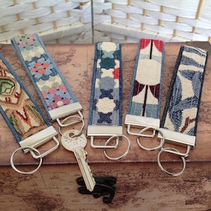 May include: Five fabric key fobs with silver-toned metal hardware and split rings. Each fob features a unique woven pattern in various colours including red, blue, green, and tan. One silver-toned metal key is attached to the second key fob from the left.