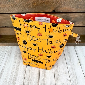 May include: Orange Halloween treat bag with black cats, bats, pumpkins, and spiders. The bag has the text "Happy Halloween, Boo Trick or Treat!" printed on it.