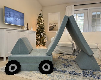 May include: A light blue fabric play structure with a car design. The structure has two large wheels and a seat. The structure is folded into a tent shape.