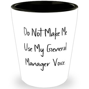 Può includere: Un bicchierino da shot in ceramica bianca con un bordo nero. Il bicchiere ha un testo nero che recita "Do Not Make Me Use My General Manager Voice."