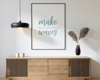 May include: A wooden cabinet with two doors and slatted panels on the sides. A black light fixture hangs above the cabinet. A framed print with the text "make waves" hangs on the wall behind the cabinet. A vase with dried flowers sits on top of the cabinet.
