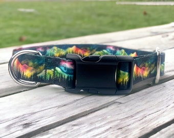 Puede incluir: Un collar de perro negro con un estampado colorido de una escena de montaña. El collar tiene un anillo en D plateado y una hebilla de plástico negra.