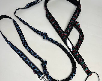 Puede incluir: Una correa para perro negra y azul con un arnés para perro negro y rojo con estampado. La correa tiene una sección elástica y un clip de metal.