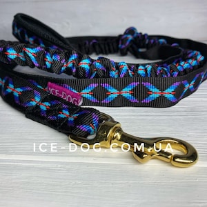 May include: Black and blue patterned dog leash with a gold metal clip. The leash has a bungee cord section and the text "ICE-DOG" is visible on the leash.