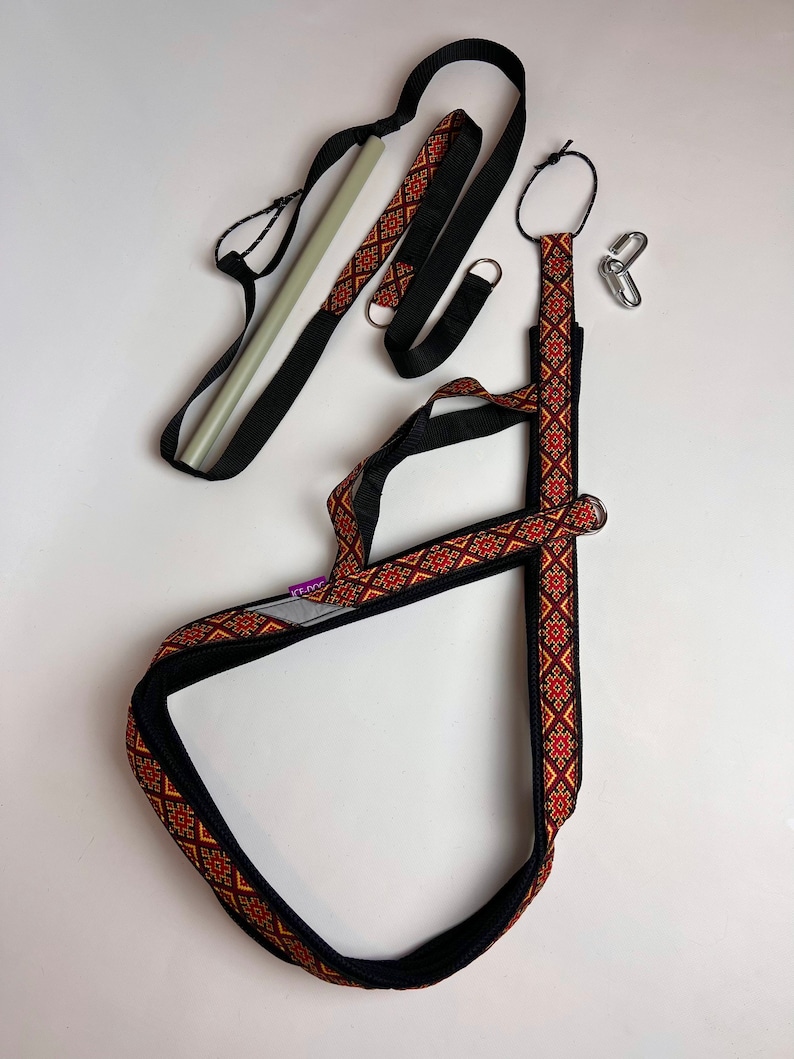 以下が含まれることがあります： 黒と赤の模様のストラップ、黒いストラップ、白いポール。ストラップには金属製のリングとフックが付いています。