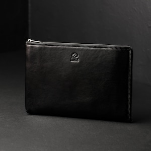 Puede incluir: Un malet&iacute;n de documentos de cuero negro con cierre de cremallera plateado. El malet&iacute;n rectangular tiene una textura suave y un peque&ntilde;o logotipo en relieve en la parte delantera. Dise&ntilde;ado para guardar documentos y otros elementos esenciales.