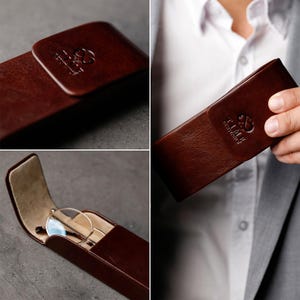 May include: A dark brown rectangular glasses case with a smooth finish and a flap closure. The exterior features an embossed logo with the text TIME RESISTANCE. The interior is lined with a light beige material and contains a pair of metal glasses.