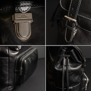 K&ouml;nnte beinhalten: Ein schwarzer Lederrucksack mit einem metallischen Druckknopfverschluss, der mit dem Text TIME RESISTANCE graviert ist, verstellbaren Schnallenriemen mit wei&szlig;en N&auml;hten, einer seitlichen Rei&szlig;verschlusstasche und einem Kordelzug mit Lederb&auml;ndern.