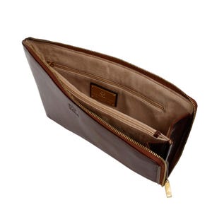 Puede incluir: Malet&iacute;n de documentos de cuero marr&oacute;n abierto con cremallera dorada e interior marr&oacute;n claro. El malet&iacute;n tiene forma rectangular y un peque&ntilde;o emblema dorado en el interior. La cremallera est&aacute; parcialmente abierta.