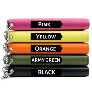 Può includere: Cinque portafogli in pelle impilati uno sopra l'altro. I portafogli sono nei seguenti colori, dall'alto verso il basso: rosa, giallo, arancione, verde militare e nero. Ogni portafoglio ha una catena metallica.